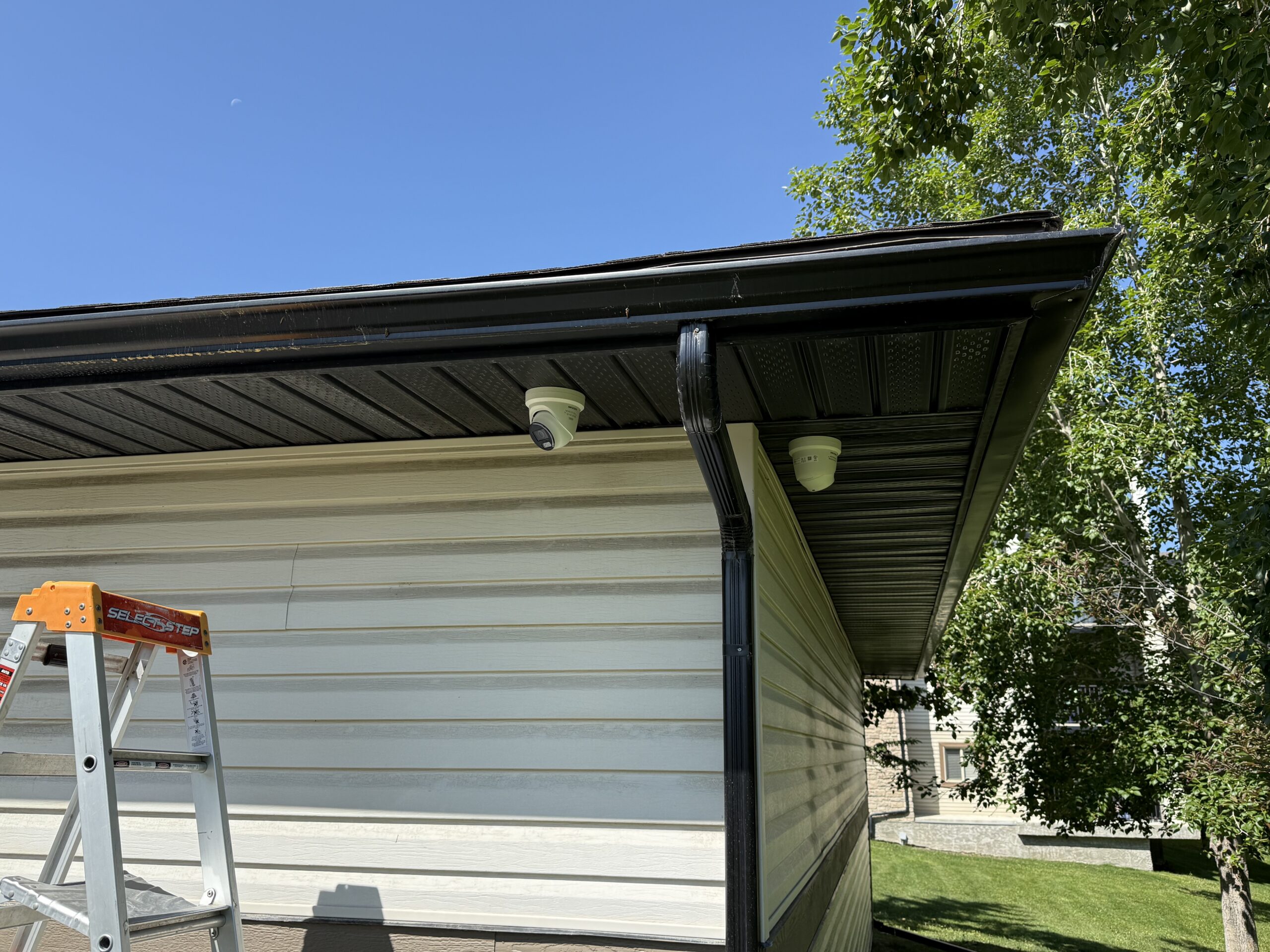 Two residential cameras installed neatly under a soffit