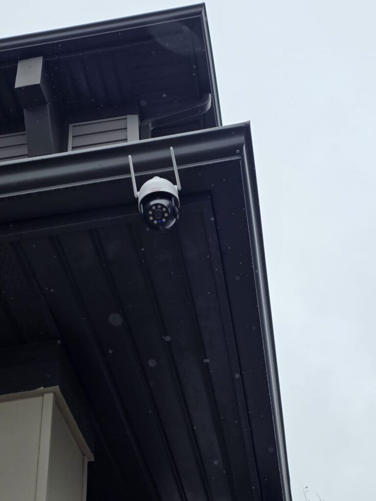 Outdoor security camera mounted beneath the dark roof eaves of a Calgary house